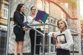 Three women with folders standing outside building and looking in documents Royalty Free Stock Photo