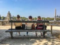 Three women friends sit on Tuileries bench facing Place de la Concorde, Paris, France