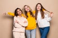 Three women friends standing together on beige background Royalty Free Stock Photo