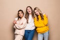 Three women friends standing together on beige background Royalty Free Stock Photo