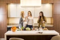 Three women friends toasting white wine in modern kitchen Royalty Free Stock Photo