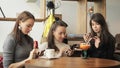 Three women girlfriends in a cafe are browsing their mobile phones. Friendly meeting in the cafe