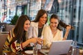 Three women have fun on laptop at cafe,