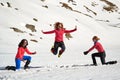 Three women hikers playing and jumping in the snow in Bucegi mountains, Romania