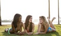 Three women lying on their belly, on the grass in a park. Royalty Free Stock Photo