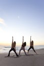 Three Women Practicing Yoga on Beach At Sunrise Royalty Free Stock Photo