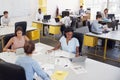 Three women share a desk in a busy office, elevated view Royalty Free Stock Photo