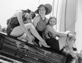 Three women sitting on top of a piano