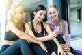 Three young women surfing internet using smartphone after workout at yoga class Royalty Free Stock Photo