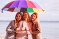 Three women under colorful umbrella