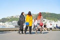 Three women walking away along along Great harbour Walk on city`s water edge
