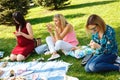 Three woman in summer green park looking in their smartphones