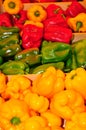 Three wood boxes , filled with red, green and yellow, bell peppers