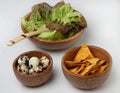 Three wooden bowls with fresh green salad, quail e