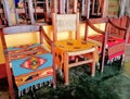 Three wooden chairs with colorful patterned hand-woven rugs at an artisan shop in Mexico.