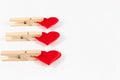 Three wooden clothespins with a metal spring hold a red heart on a white wooden table background Royalty Free Stock Photo