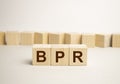 Three wooden cubes with letters - BPR - short for Business process reengineering, on blue table, space for text in right. Front Royalty Free Stock Photo