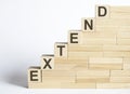 Three wooden cubes with letters EXTEND on white table