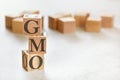 Three wooden cubes with letters GMO means genetically modified organism , on white table, more in background, space for