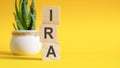 IRA concept with wooden blocks on table, yellow background