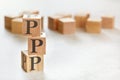 Three wooden cubes with letters PPP means Praise, Picture, Push, on white table, more in background, space for text in right