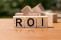 Three wooden cubes with letters ROI stands for Return on Investment on wooden table Royalty Free Stock Photo