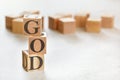 Three wooden cubes with word GOD, on white table, more in background, space for text in right down corner Royalty Free Stock Photo