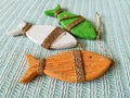 Three wooden decorative fish of red, green and white, tied with twine