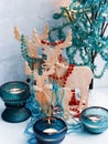 Three wooden deer in the form of a family, decorated with garlands, decorative tree with lights in turquoise colors