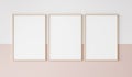 Three wooden frames on pink and white wall, frame mockup