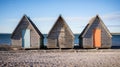 Three wooden huts on a beach on a sunny day