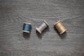 Three wooden spools with blue, yellow and gray threads on a wooden table, background for sewing, needlework, handmade layout Royalty Free Stock Photo