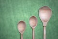 Three wooden spoons of different sizes on a green background close-up Royalty Free Stock Photo