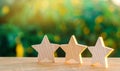 Three wooden stars on a background of green bokeh background. The concept of the rating of hotels and restaurants, the evaluation