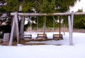 Three wooden swings in a backyard in winter