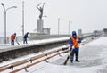 Three workers clear the subway station from snow during a heavy snowfall