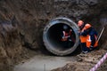 Three workers install concrete gutters on the side of the road, power plants. Frame lifting concrete drainage pipe. Russia Royalty Free Stock Photo