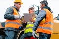 Three workers in a quarry discussing in front of heavy machinery Royalty Free Stock Photo