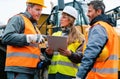 Three workers in a quarry discussing in front of heavy machinery Royalty Free Stock Photo