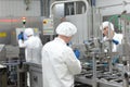 Three workers in uniforms at production line in plant