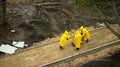 three workers in yellow raincoats at a construction site, Royalty Free Stock Photo