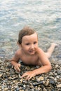 Three year boy bathes in the sea on pebbles Royalty Free Stock Photo