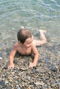 Three year boy bathes in the sea on pebbles Royalty Free Stock Photo