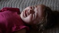 Three year old girl cries on the bed with soft light. Concept of discomfort, sadness and mistreatment Royalty Free Stock Photo