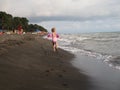 three-year-old girl runs on the beach contaminated with foam. georgia, ureki - june 2019