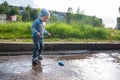 A three-year-old white boy in a blue hat, jeans and sandals plays on a cool summer day with an outdated remote control car Royalty Free Stock Photo