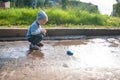 A three-year-old white boy in a blue hat, jeans and sandals plays on a cool summer day with an outdated remote control car Royalty Free Stock Photo