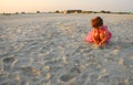 Three years old girl playing with sand on the beach