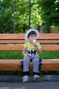 Three years stylish boy seeting on a bench in the park and enjoing an ice cream