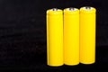 Three yellow batteries close-up on a dark black blurred background. Electrics. Battery power. Accumulator on the fabric with vill Royalty Free Stock Photo